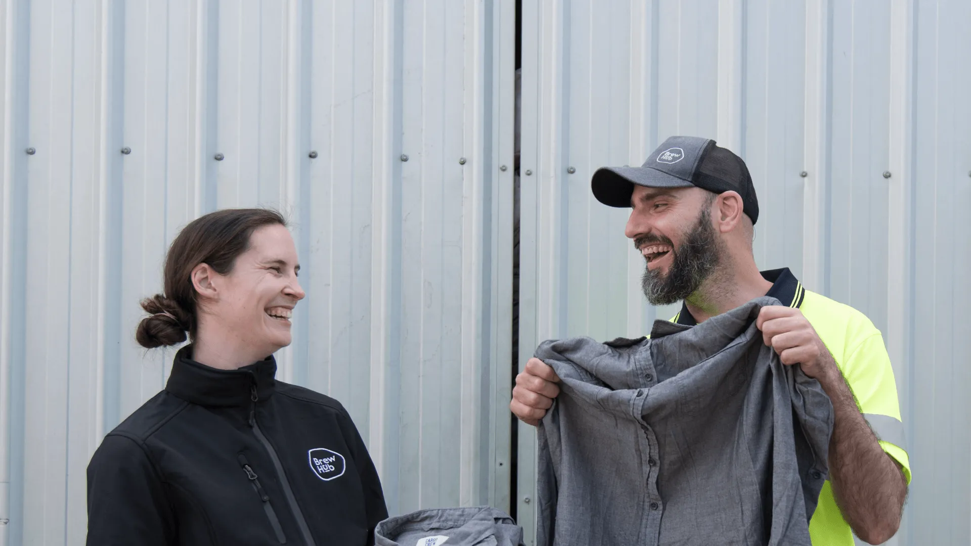 A BrewHub employee presenting uniforms to a worker as part of their uniform donation program